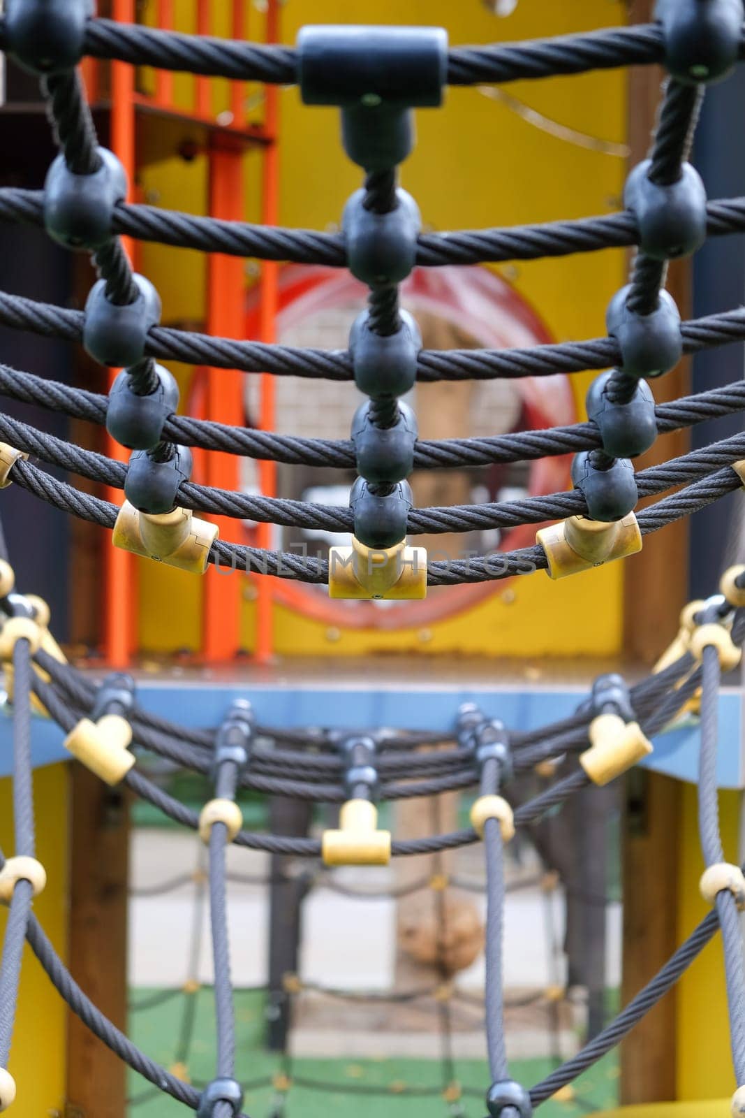 Close-up view of colorful playground rope bridge for children's outdoor recreational equipment in a public park. Ensuring safety and durability for a fun and adventurous playtime