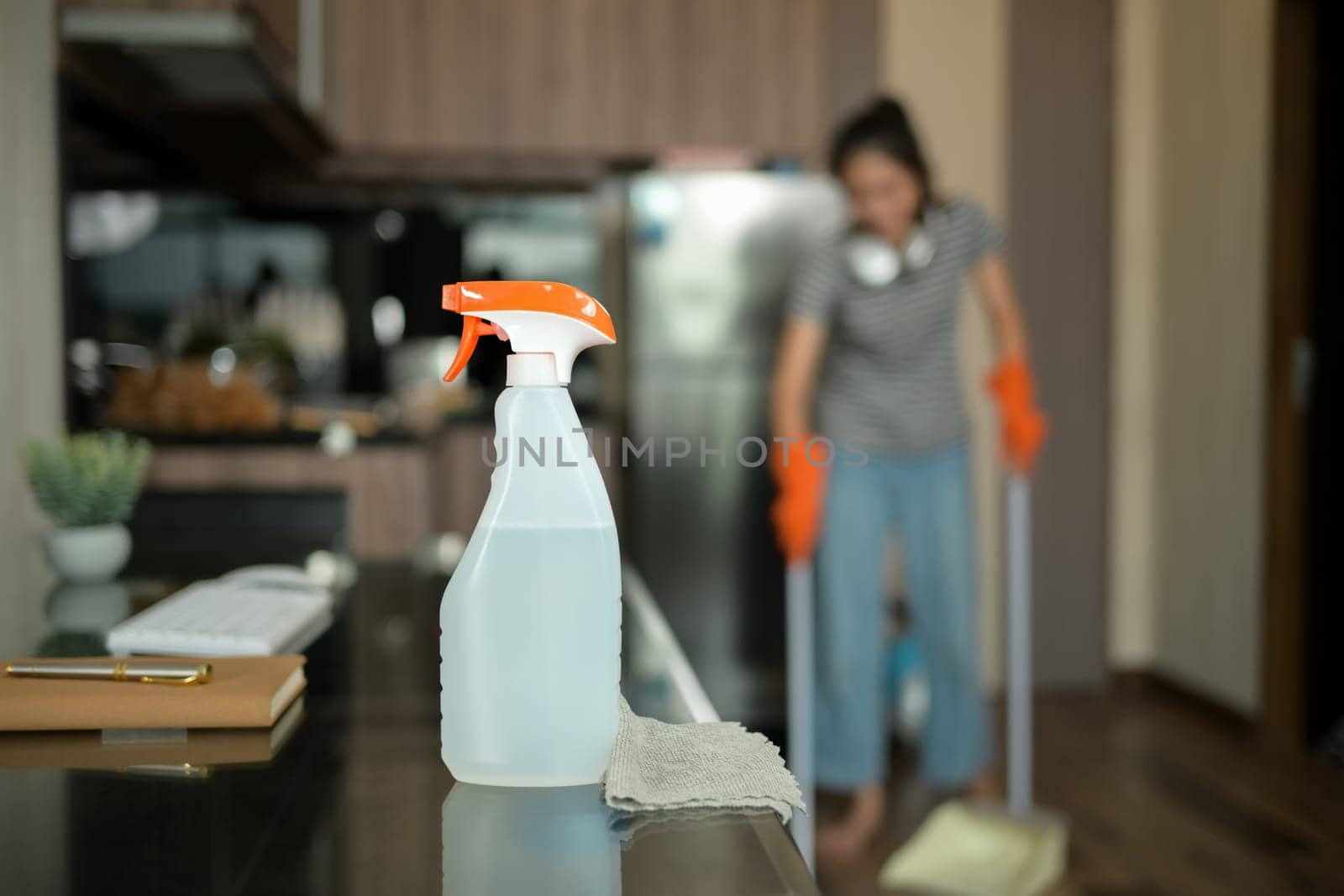 A spray bottle and rag are on glass table in the kitchen. Household and cleaning concept.