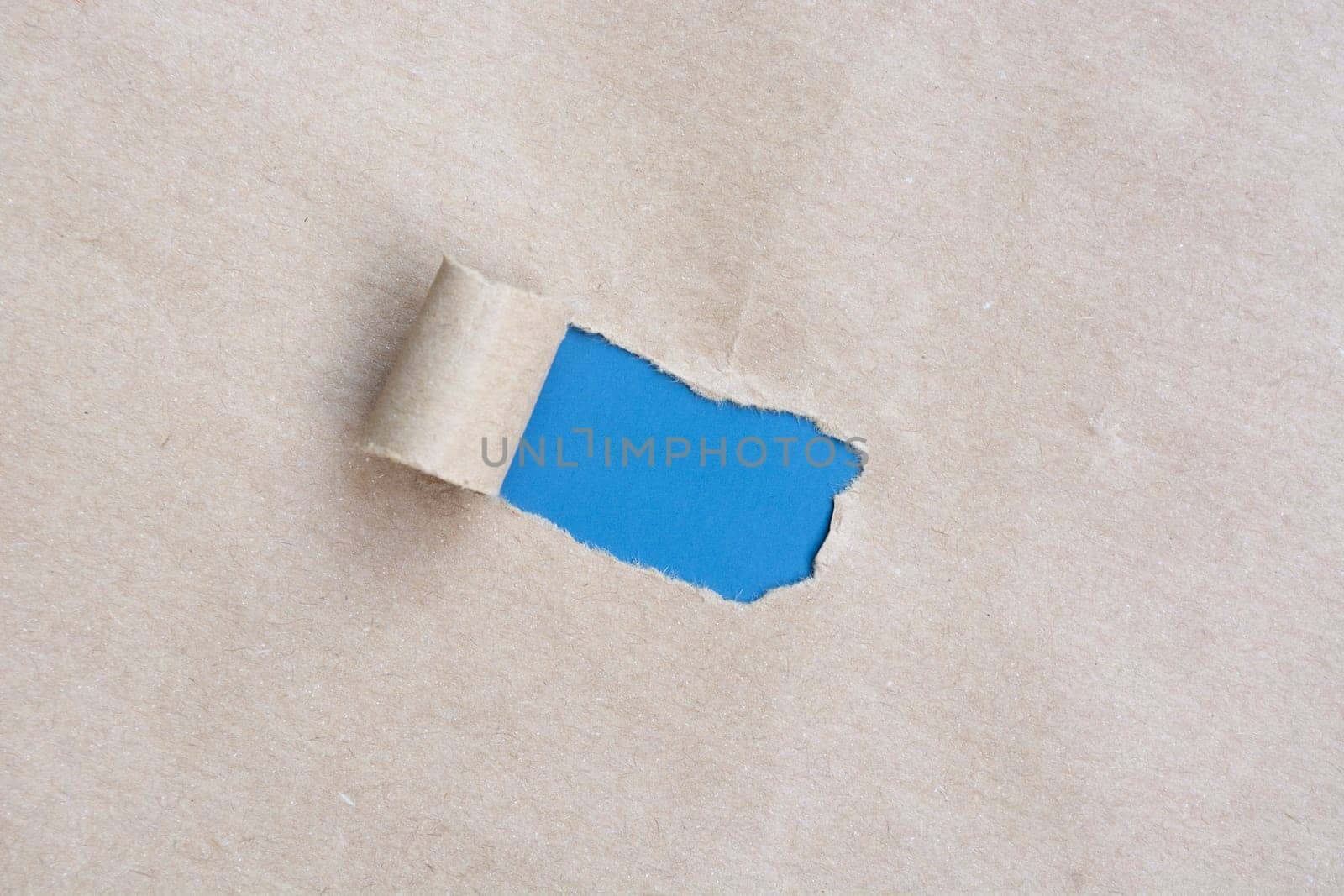 Brown paper with torn hole and rolled edge with blue background.