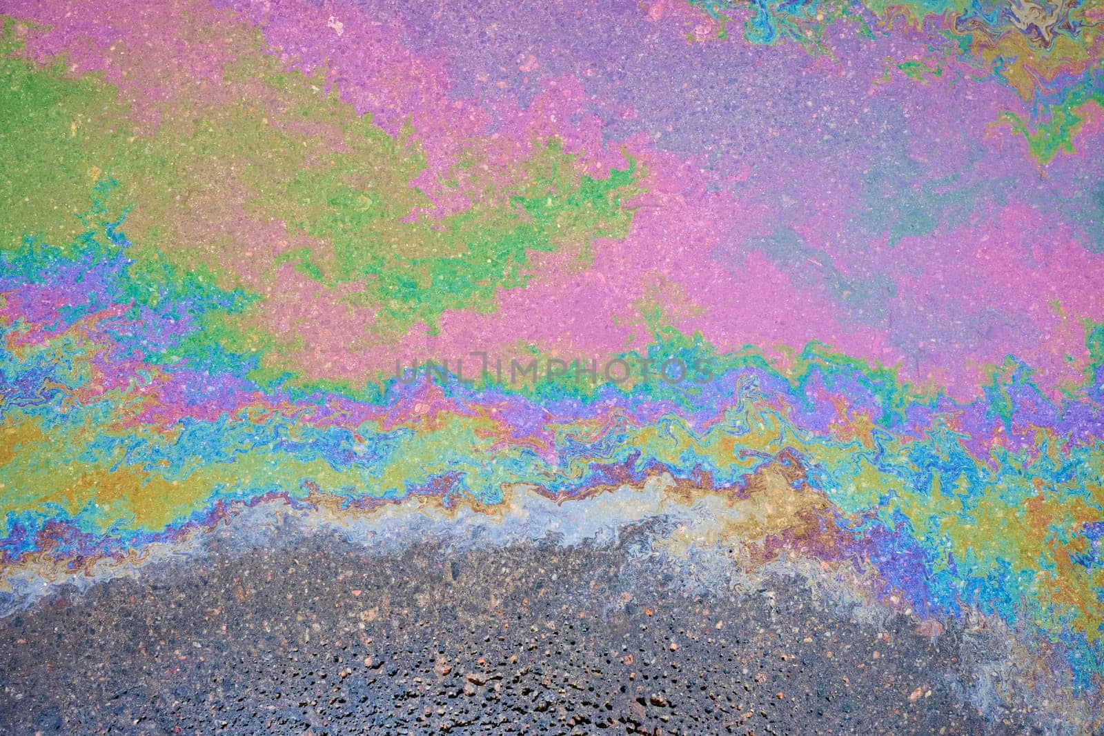 Oil stains from leaks in the car engine. Oil after rain makes spots with rainbow reflections refractive sun spectrum. by AliaksandrFilimonau