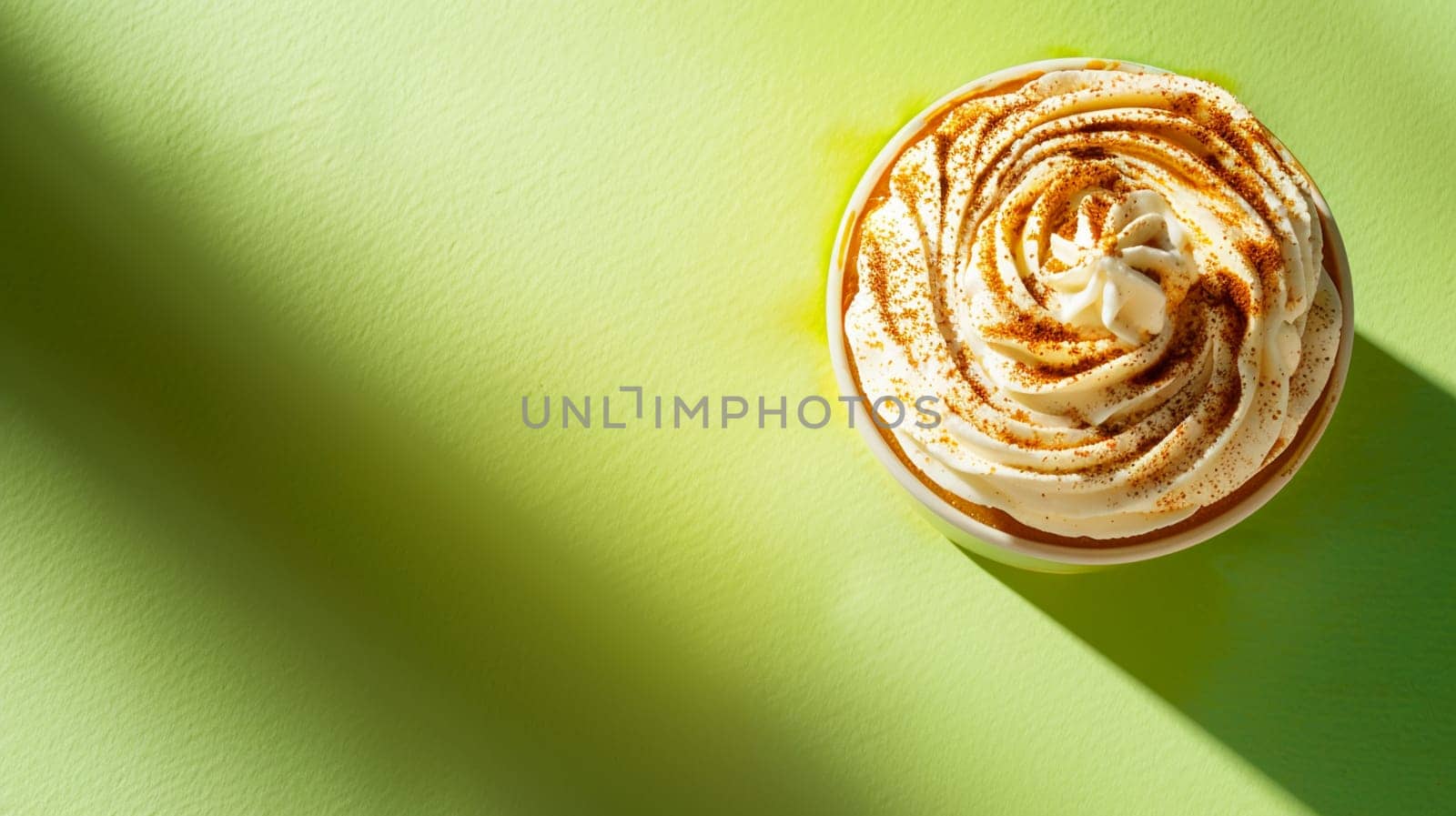 Top view of sweet cupcake with creamy frosting dusted with cinnamon, vibrant green background, dessert concept shadow play