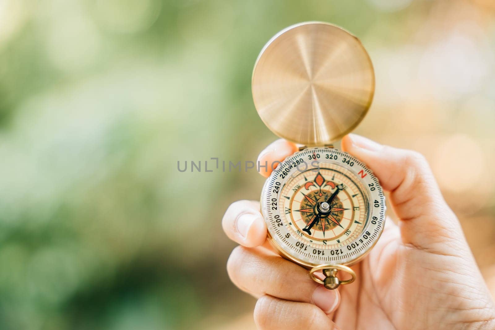 With a picturesque forest and tranquil lake in the background a woman's hand securely holds a compass symbolizing guidance and the exciting exploration that awaits.