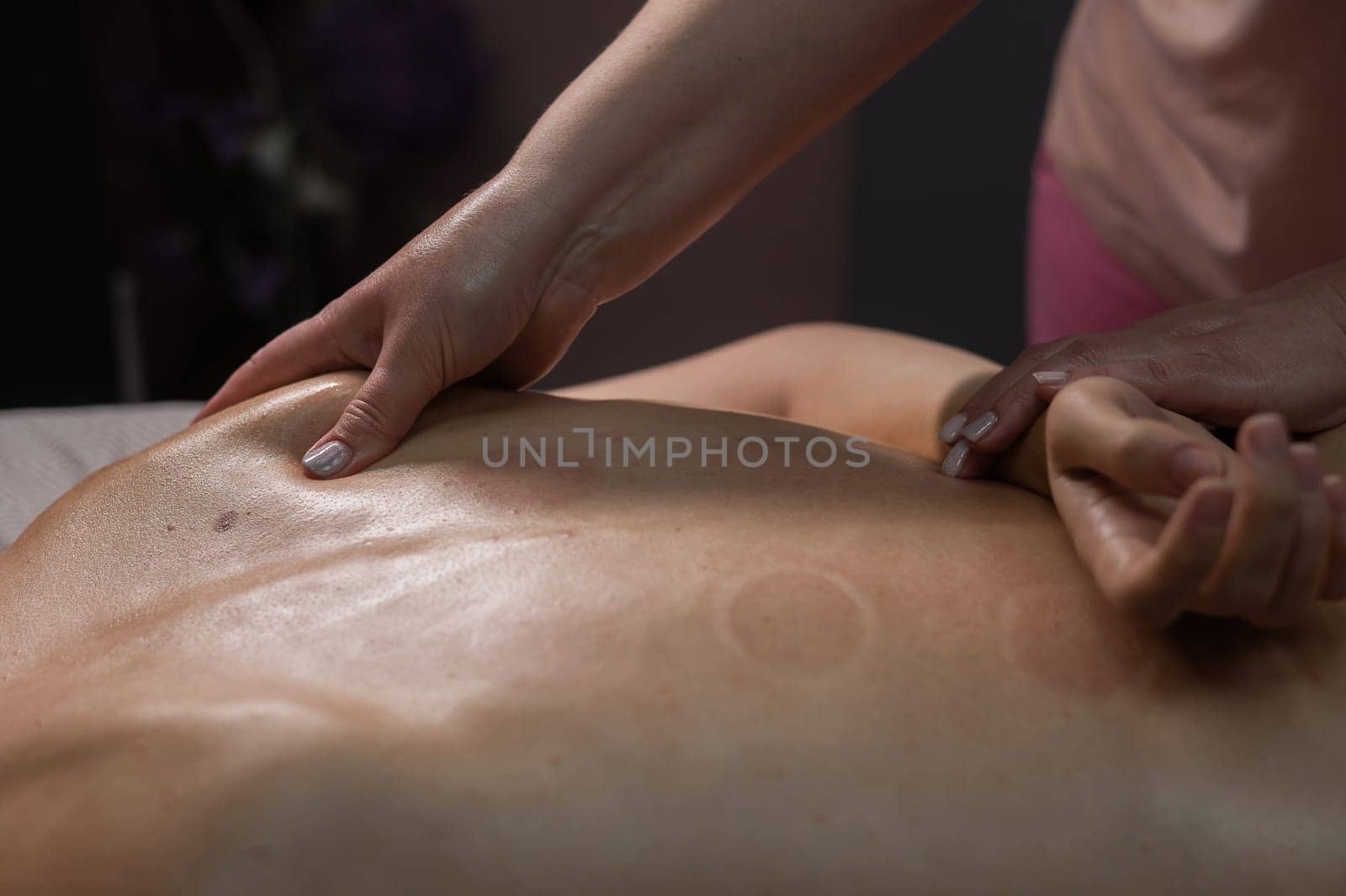 Woman having a therapeutic back massage. The masseur kneads the muscles under the shoulder blade. by mrwed54