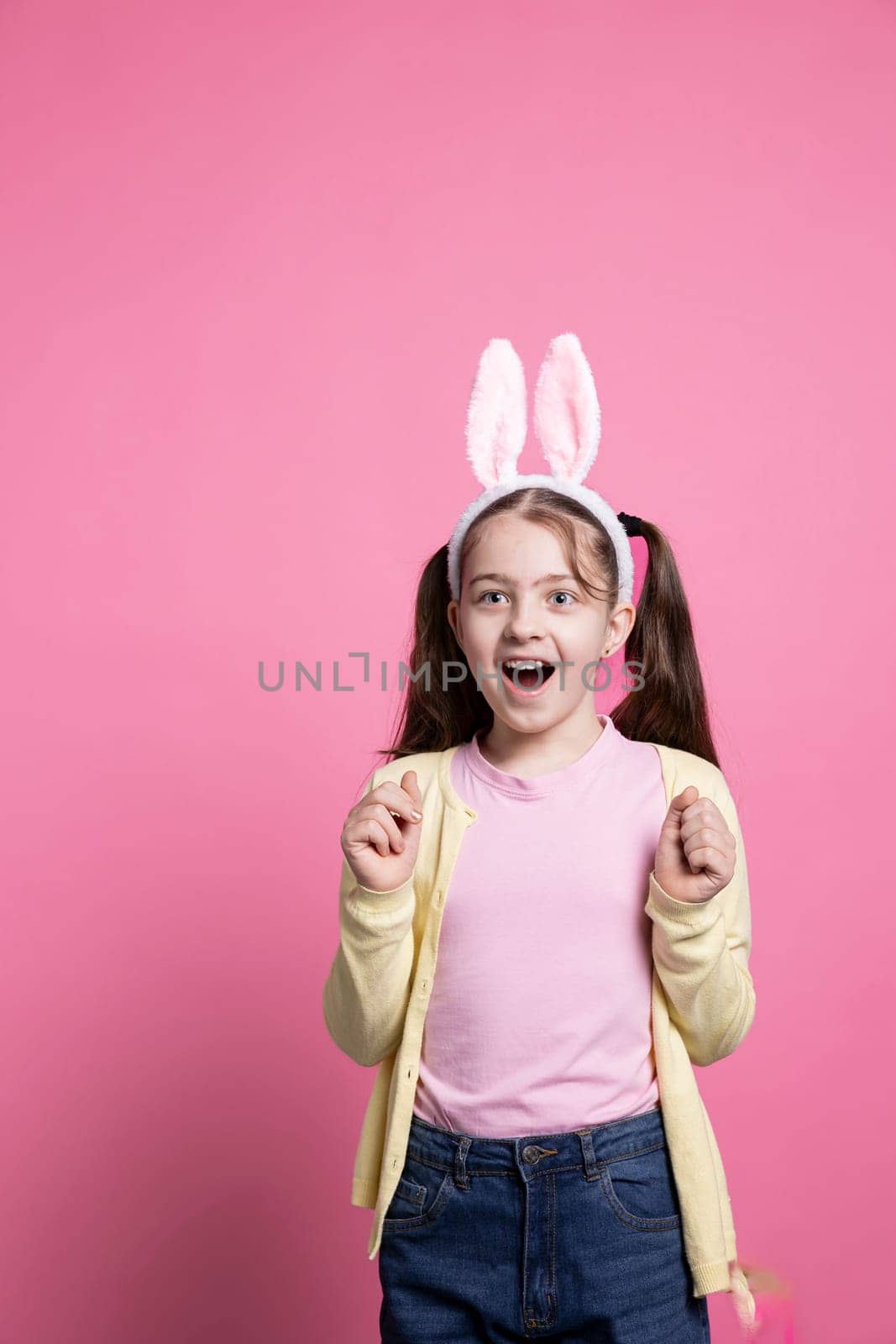 Excited optimistic girl acting amazed by easter presents in studio, feeling happy with her gifts and celebrating spring holiday. Little enthusiastic child getting joyful about april celebration.