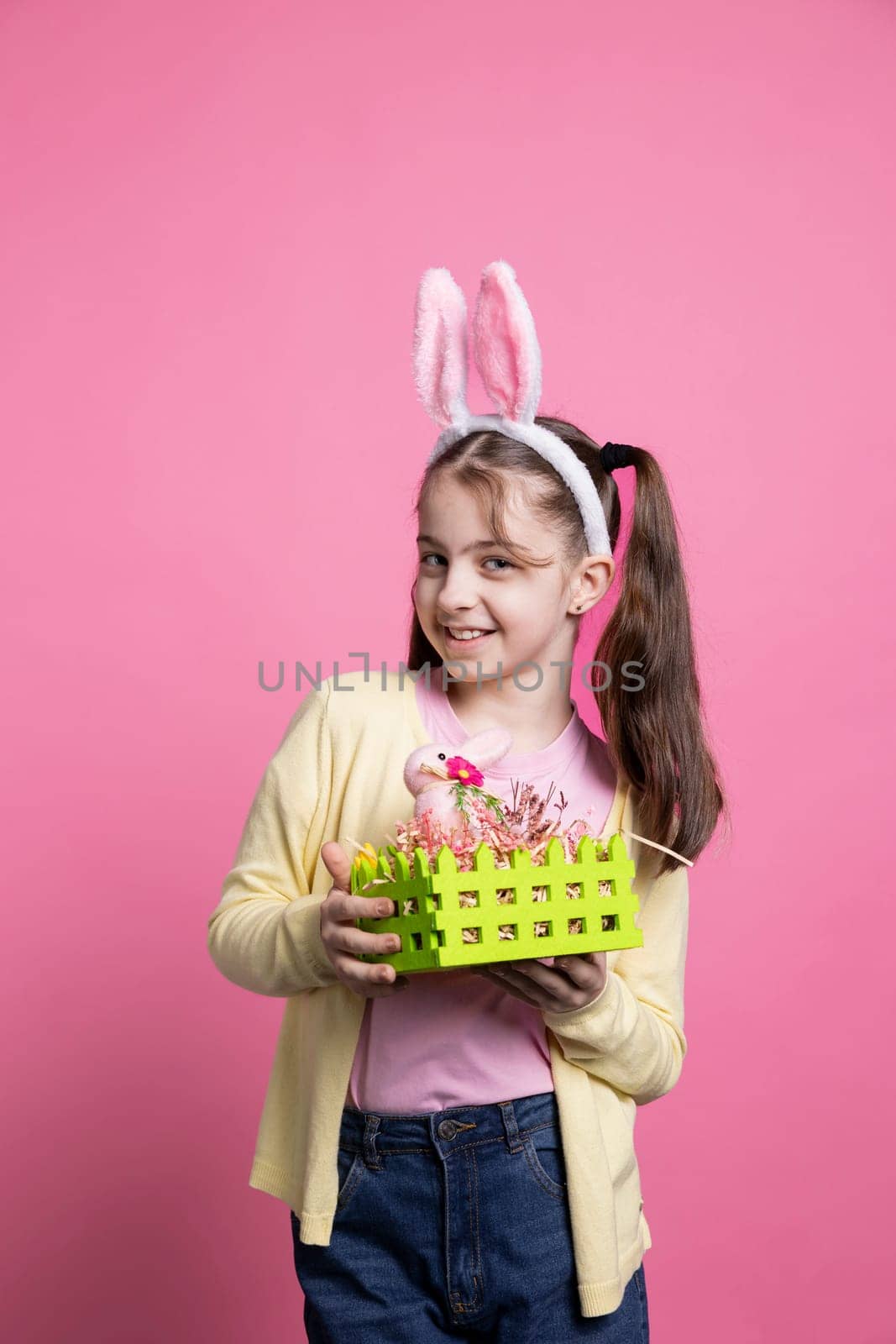 Little joyful child holding basket with painted eggs and a pink rabbit by DCStudio