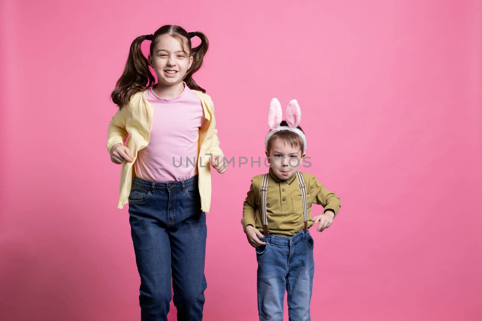 Brother with bunny ears and sister jumping around in the studio by DCStudio