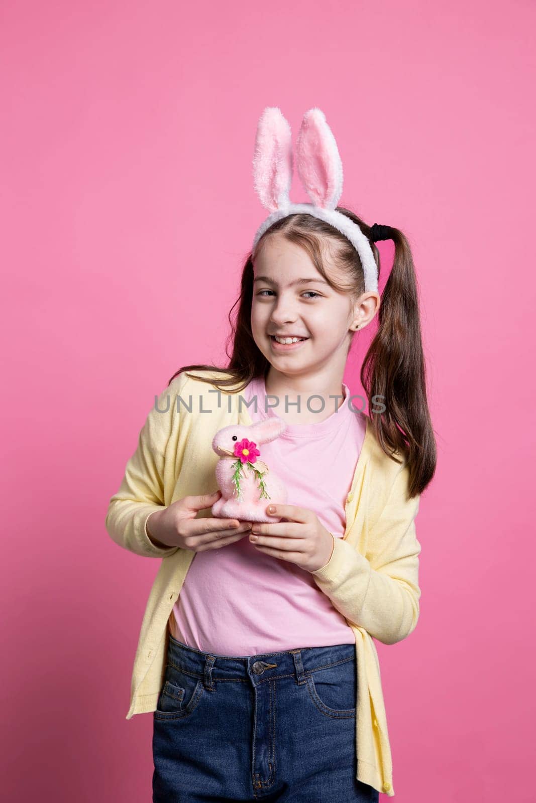 Cheerful small kid posing with a pink rabbit toy on camera by DCStudio