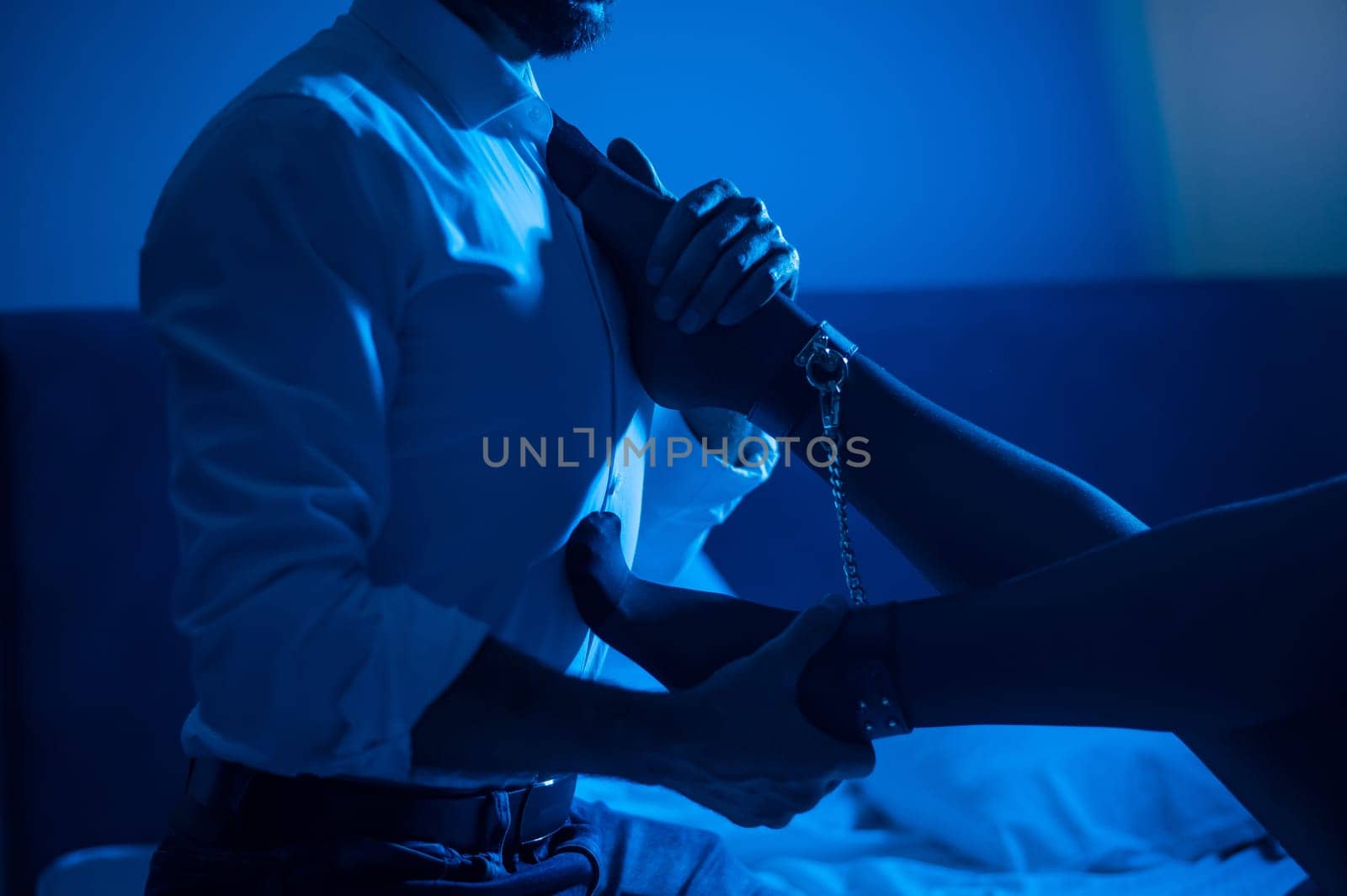 A man holds a woman by the ankles. BDSM concept