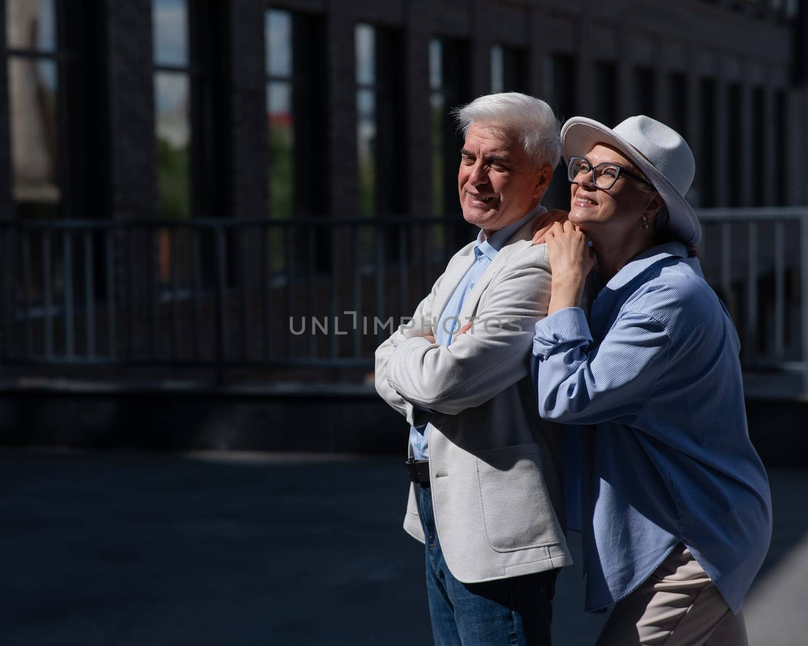 Stylish mature couple on a walk. Portrait of gray-haired man and woman hugging outdoors. by mrwed54