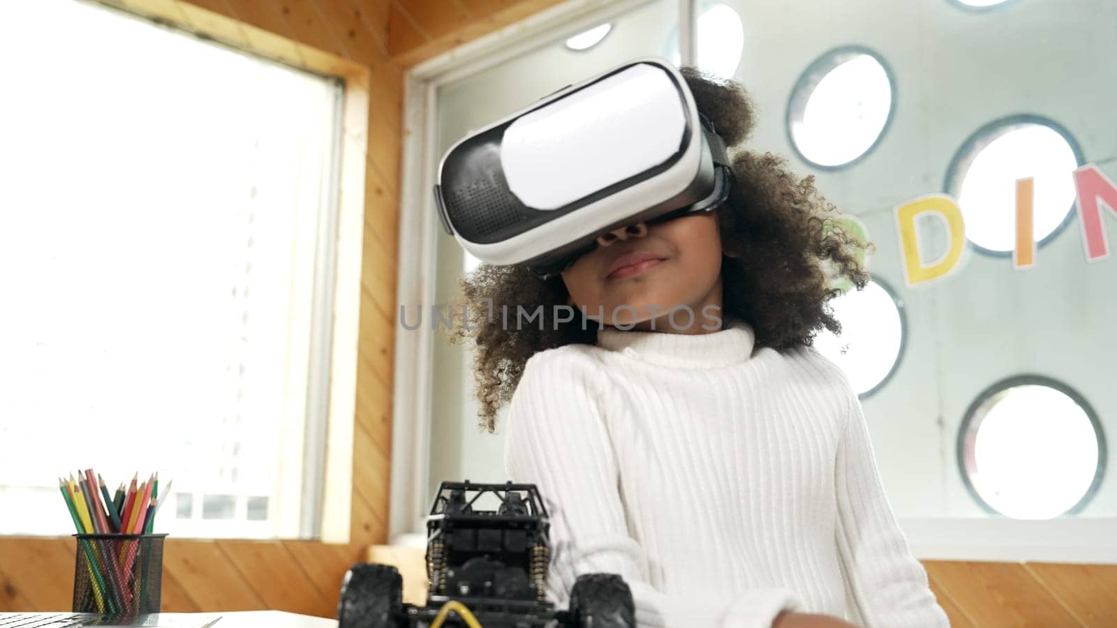 Smart african girl wearing VR vision glasses while hold car model. Student study visual reality and holding robotic model. Child using technology gadget in online education in STEM class.Erudition.