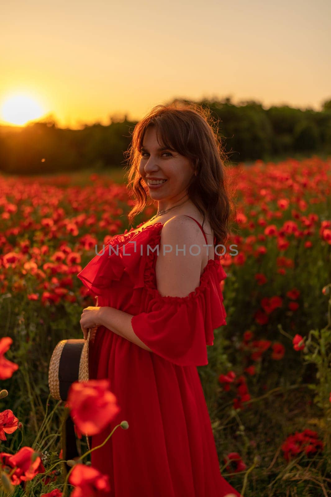 Woman poppy field red dress sunset. Happy woman in a long red dress in a beautiful large poppy field. Blond stands with her back posing on a large field of red poppies.
