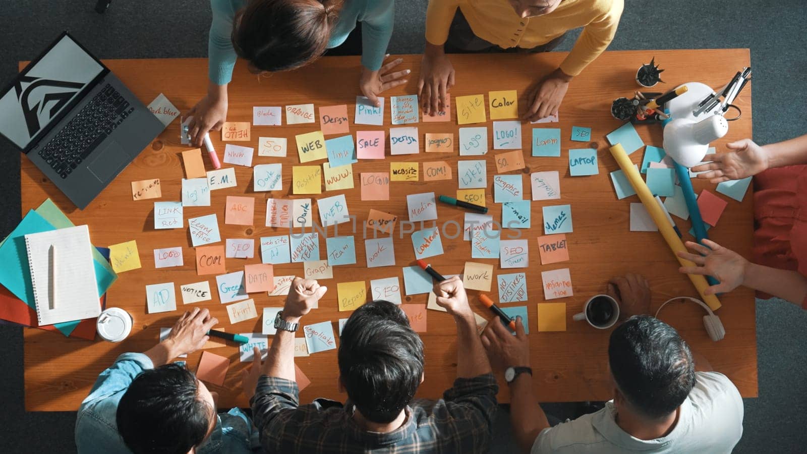 Top view of manager looking at idea on sticky notes and explain idea about web design. Skilled marketing team or programmer brainstorming idea while looking at tablet with color palette. Symposium.