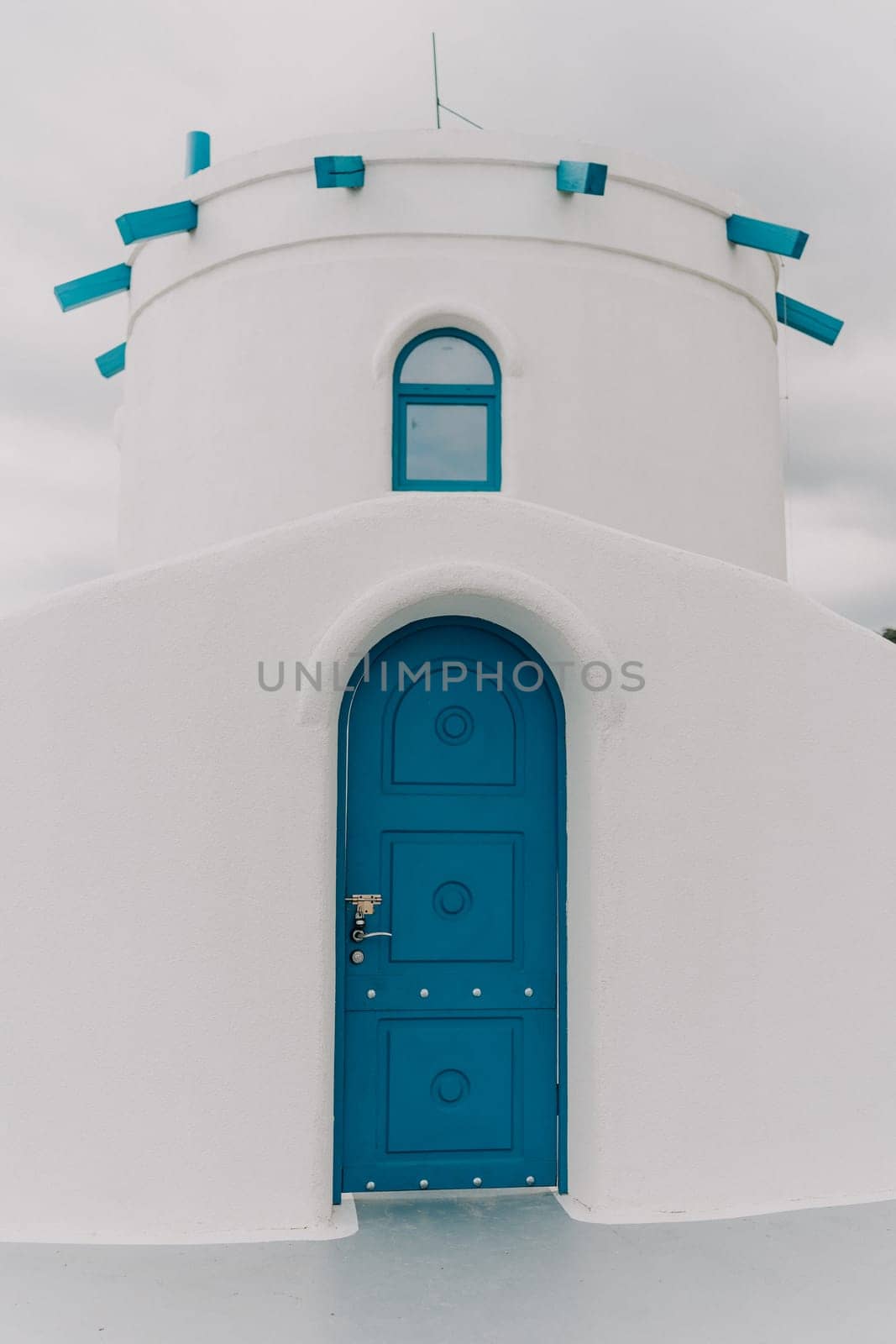 A blue door with a lock sits in front of a white building. The door is the only visible part of the building, and it is blue in color. by Matiunina