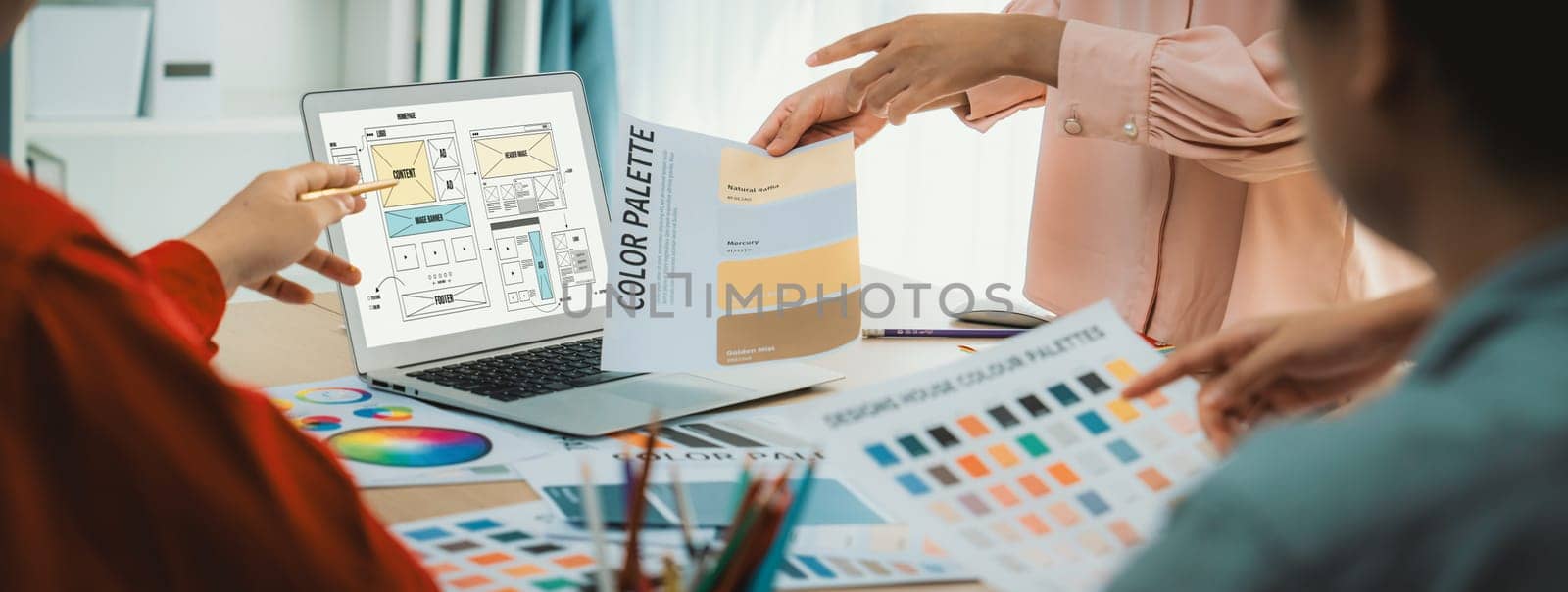 Cropped image of interior designer team discuss the material color while laptop displayed website wireframe designs for mobiles app and website. Creative design and business concept. Variegated.