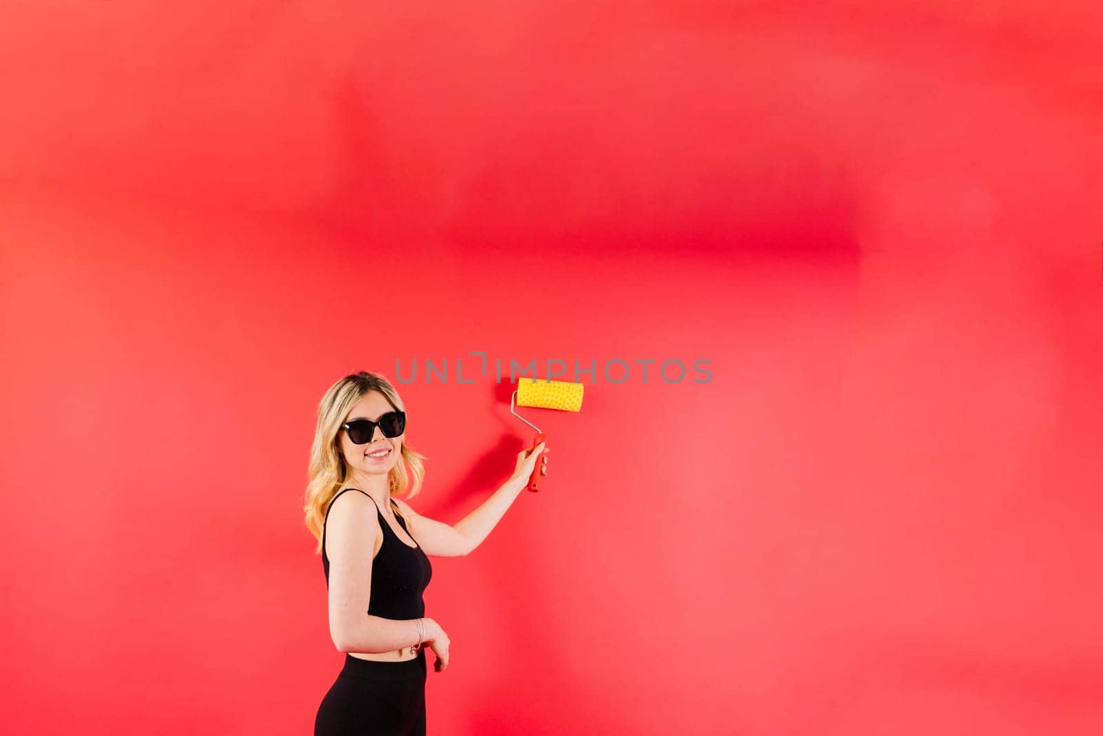 Young woman with roller brush on red white backgrounds Instruments accessories for renovation room