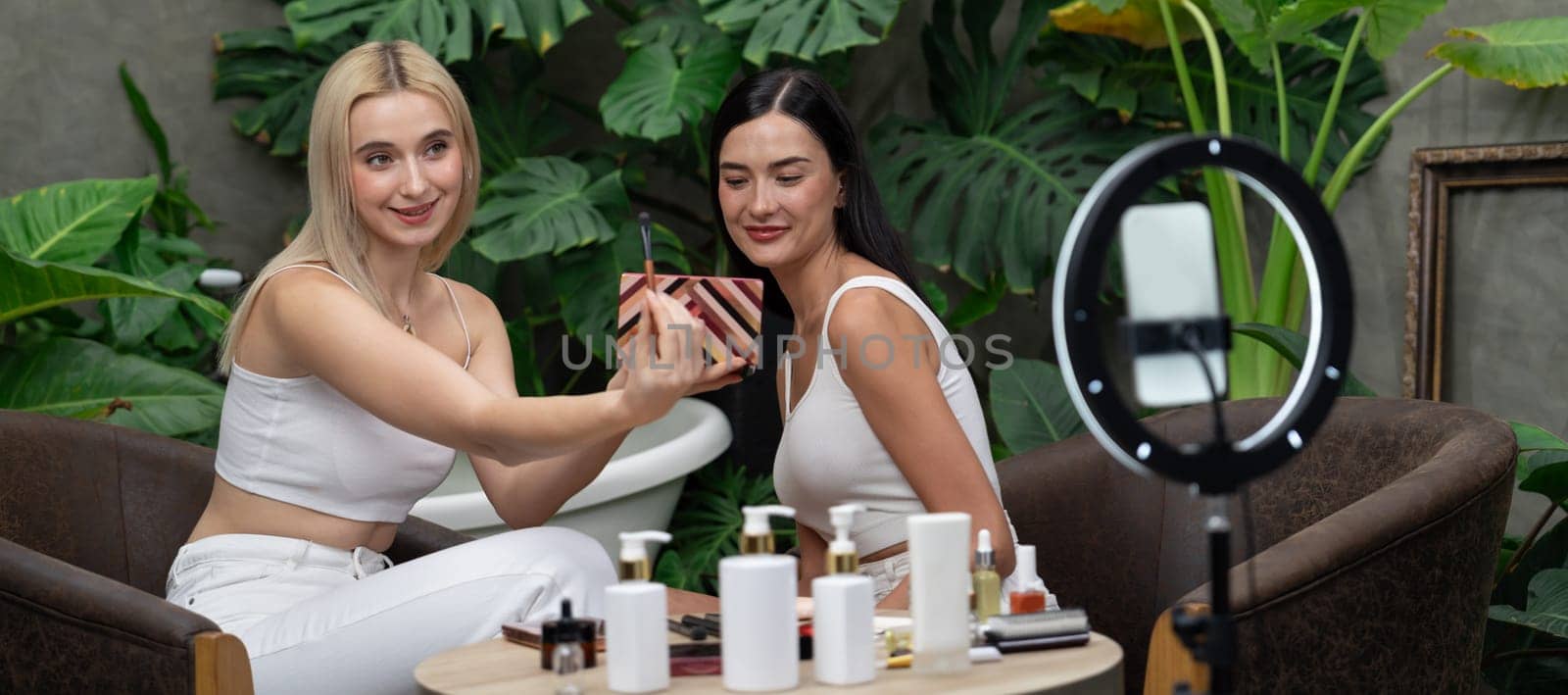 Two beautiful content creator making natural beauty and cosmetic tutorial on green garden. Beauty blogger show how to beauty care video to social medial audience using selfie stick.Panorama Blithe