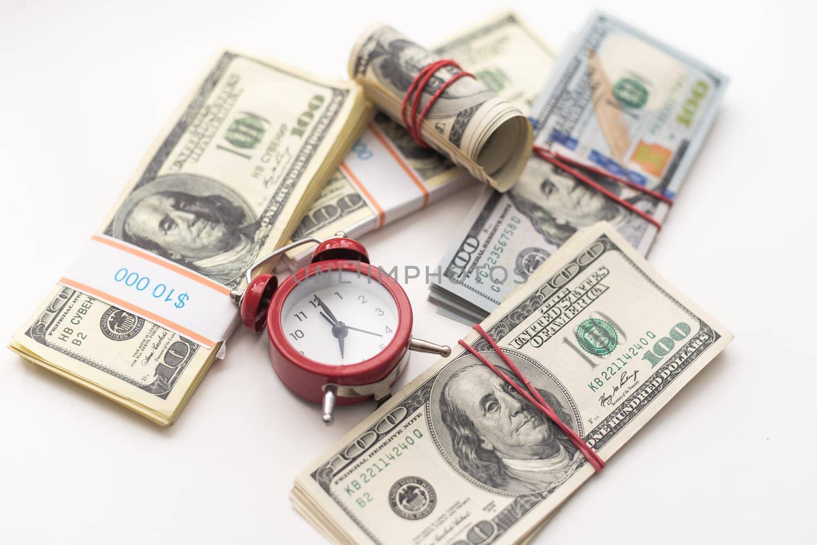 One dollar bills on a wooden table with a red alarm clock in the composition. Money saving concept. . High quality photo