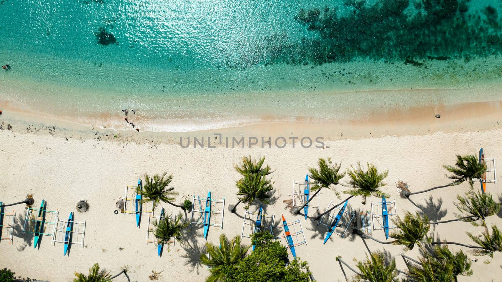 Aerial view of sandy beach with palm trees and sea surf with waves. Pagudpud, Ilocos Norte Philippines