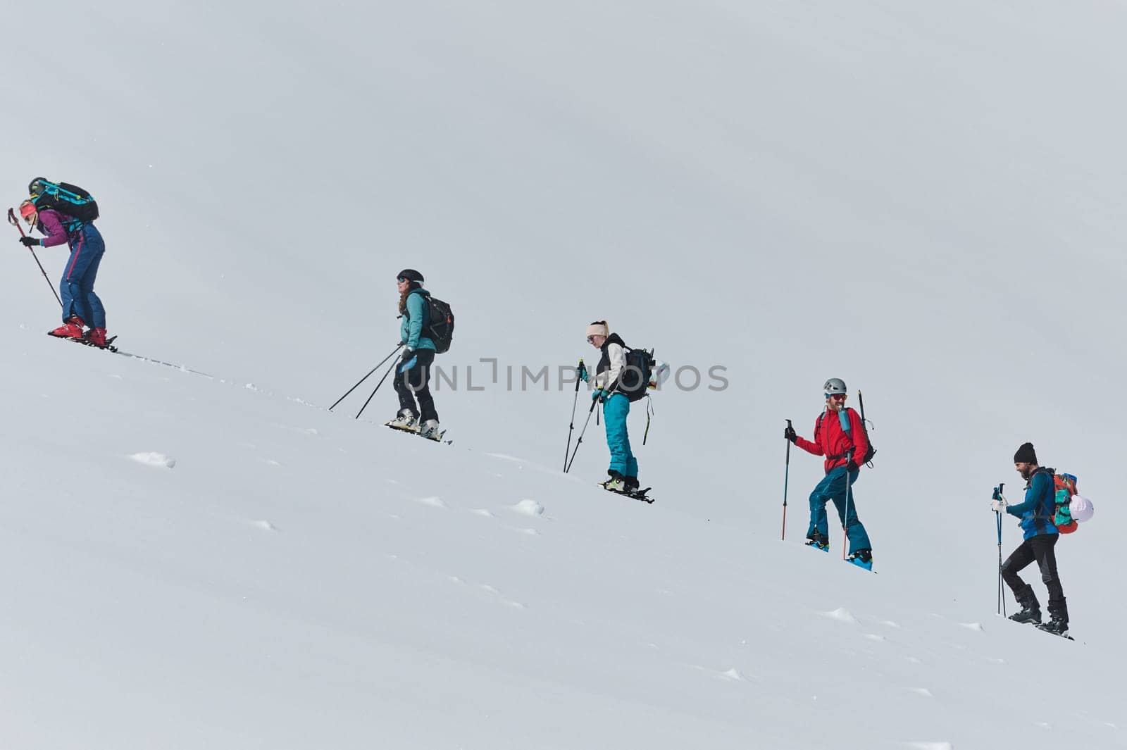 A group of professional ski mountaineers ascend a dangerous snowy peak using state-of-the-art equipment.