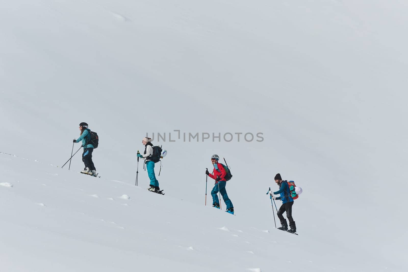 A group of professional ski mountaineers ascend a dangerous snowy peak using state-of-the-art equipment.