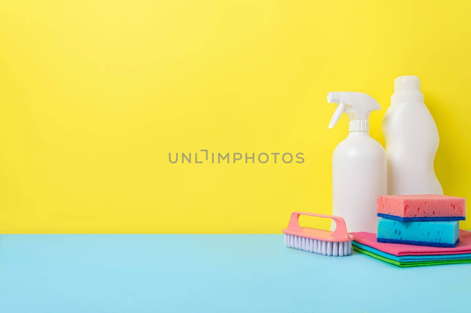 House cleaning products on yellow blue background, copy space. Cleaning service or housekeeping concept with space for text or design
