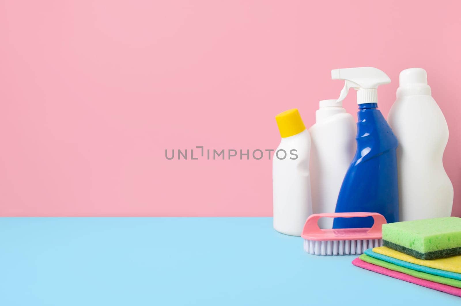 House cleaning products on blue pink background, copy space. Cleaning service or housekeeping concept with space for text or design