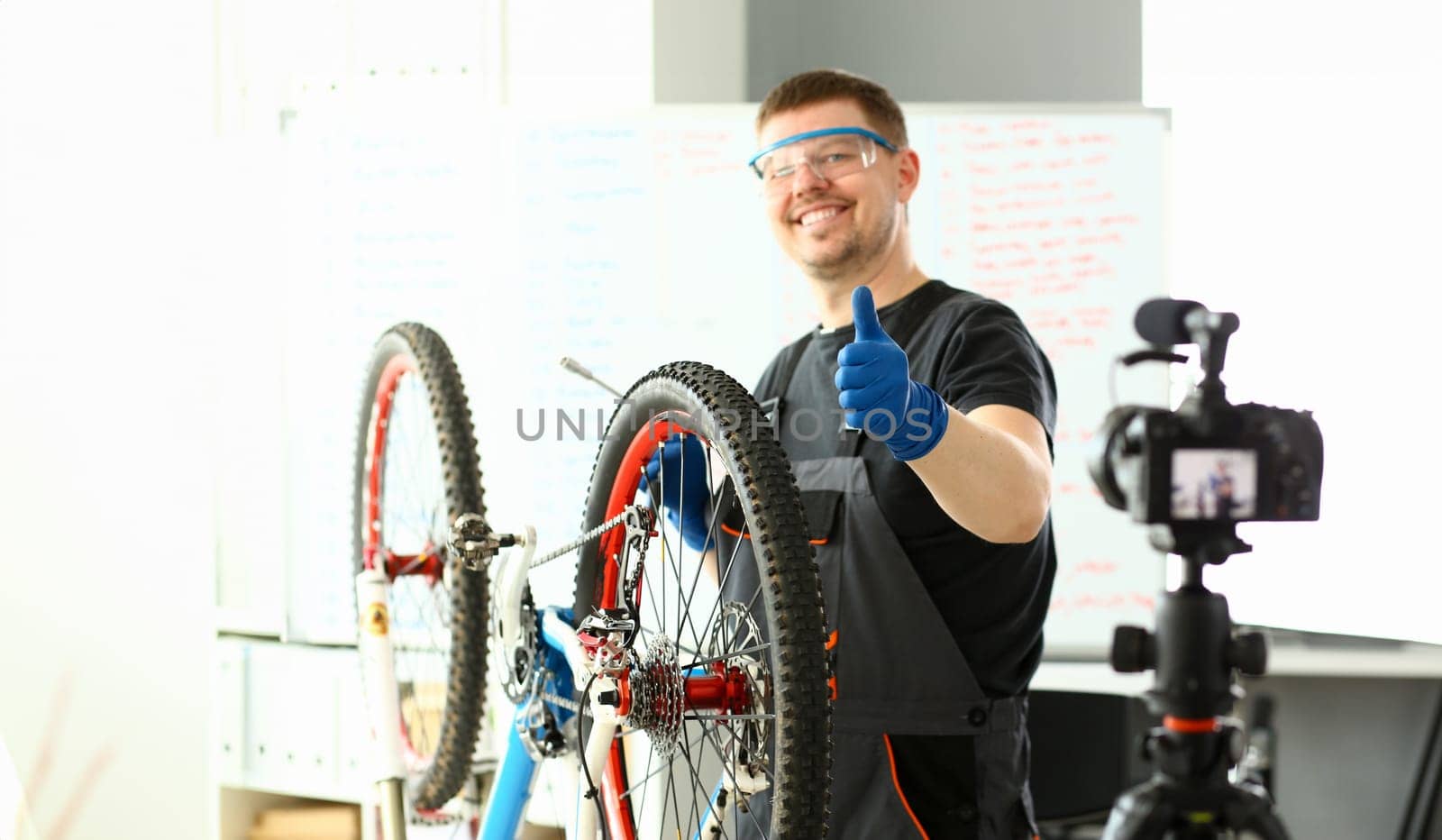 Male blogger hand service man bicycle workshop repair hold thumbs up closeup