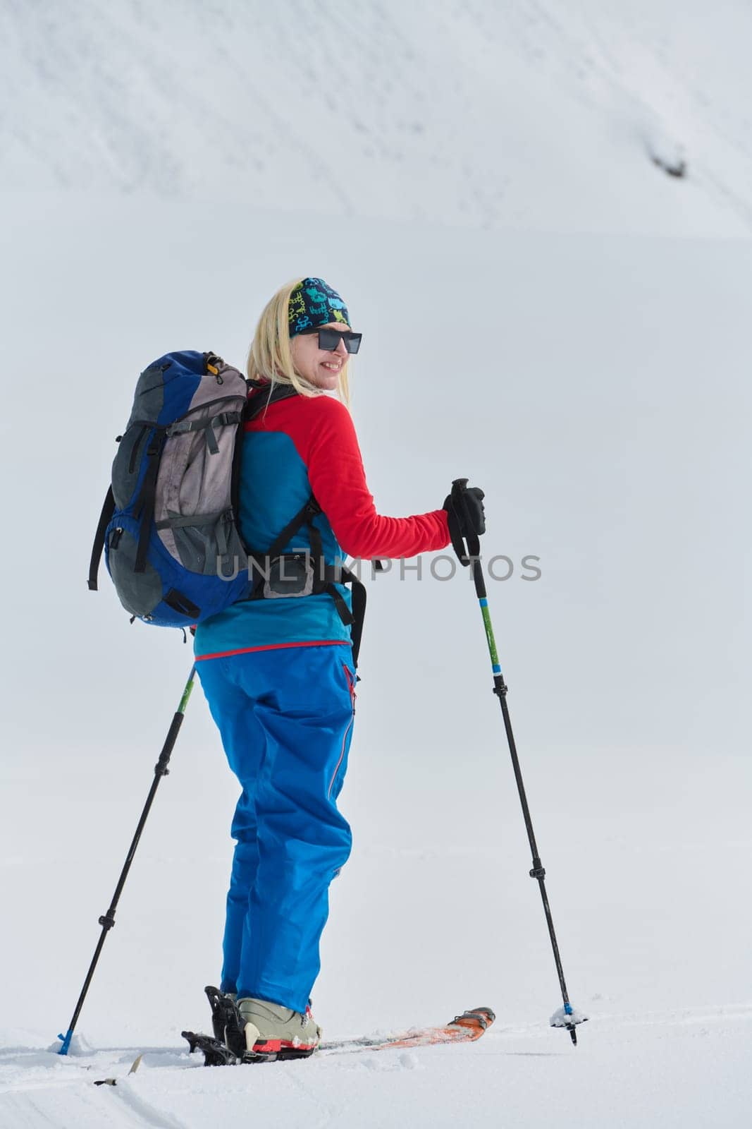 A professional woman skier rejoices after successfully climbing the snowy peaks of the Alps by dotshock