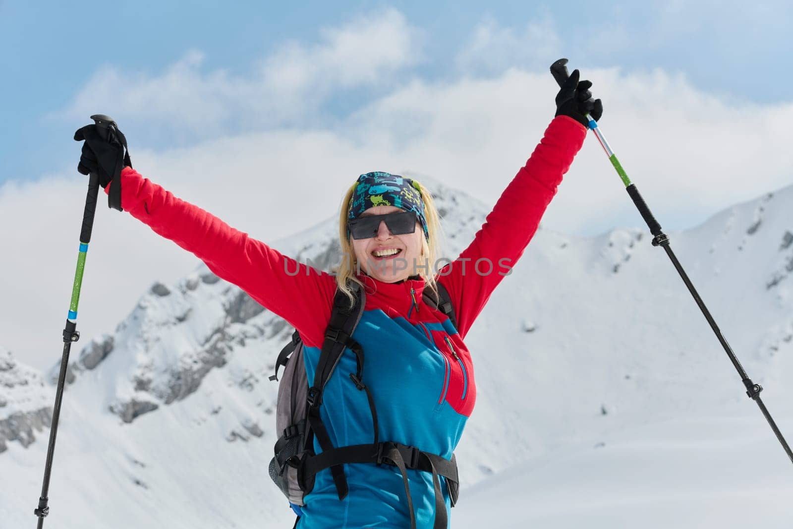 A professional woman skier rejoices after successfully climbing the snowy peaks of the Alps by dotshock