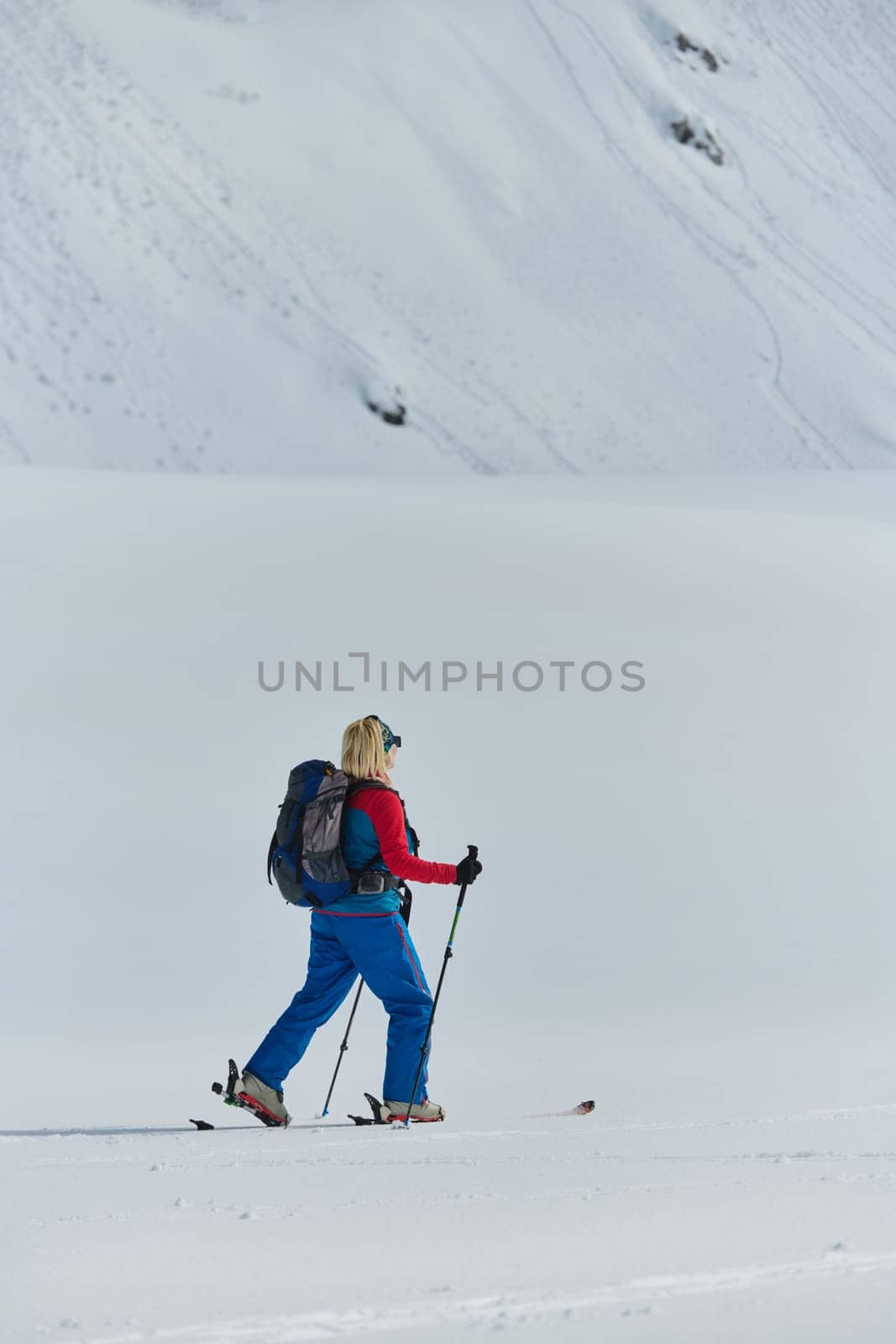 A determined skier scales a snow-capped peak in the Alps, carrying backcountry gear for an epic descent