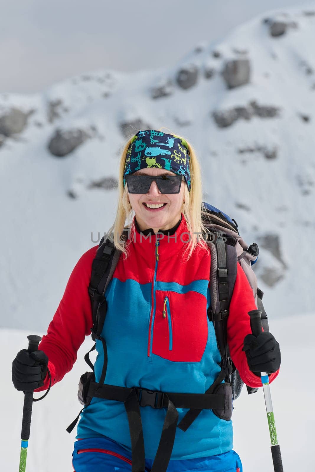 A professional woman skier rejoices after successfully climbing the snowy peaks of the Alps.