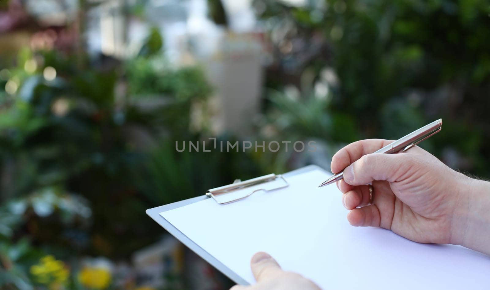 Human Hand Writing on Clipboard with White Paper. Man Holding Pen and Blank Document Close-up Photography. Business Paperwork for Making Notes. Male Person Sign Document Page Partial View Photo