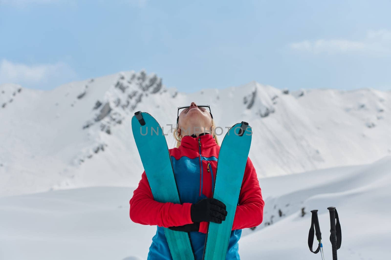 A professional woman skier rejoices after successfully climbing the snowy peaks of the Alps.