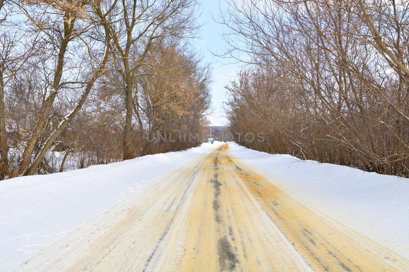 Rural winter road sprinkled with sand against ice by olgavolodina