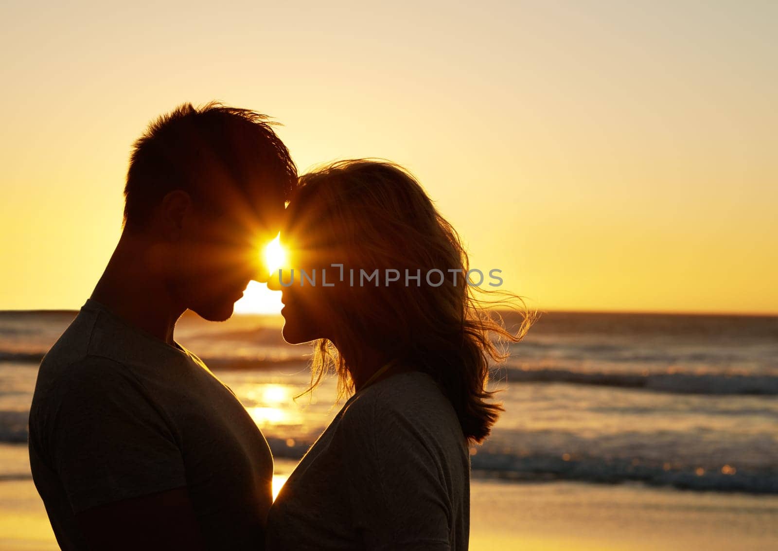 Couple, romance and kiss at beach with sunset for date or summer holiday and bonding in Florida. Relationship, commitment and love together as soulmate with smile or happy for honeymoon and vacation.