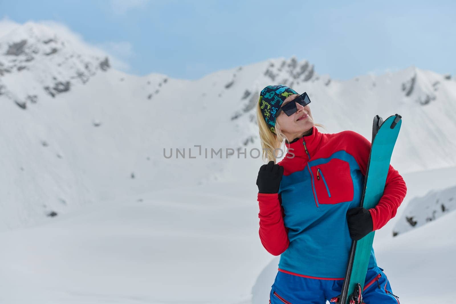 A professional woman skier rejoices after successfully climbing the snowy peaks of the Alps by dotshock