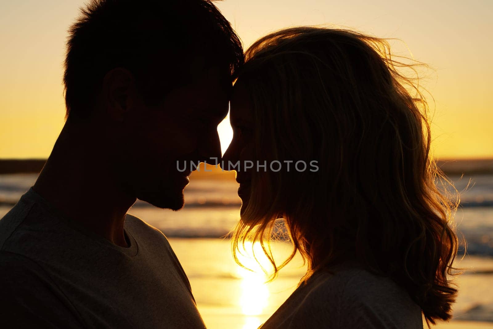 Couple, love and kiss at ocean with sunset for date or summer holiday and bonding in Florida. Relationship, commitment and romance together as soulmate with smile, fun and vacation for honeymoon.