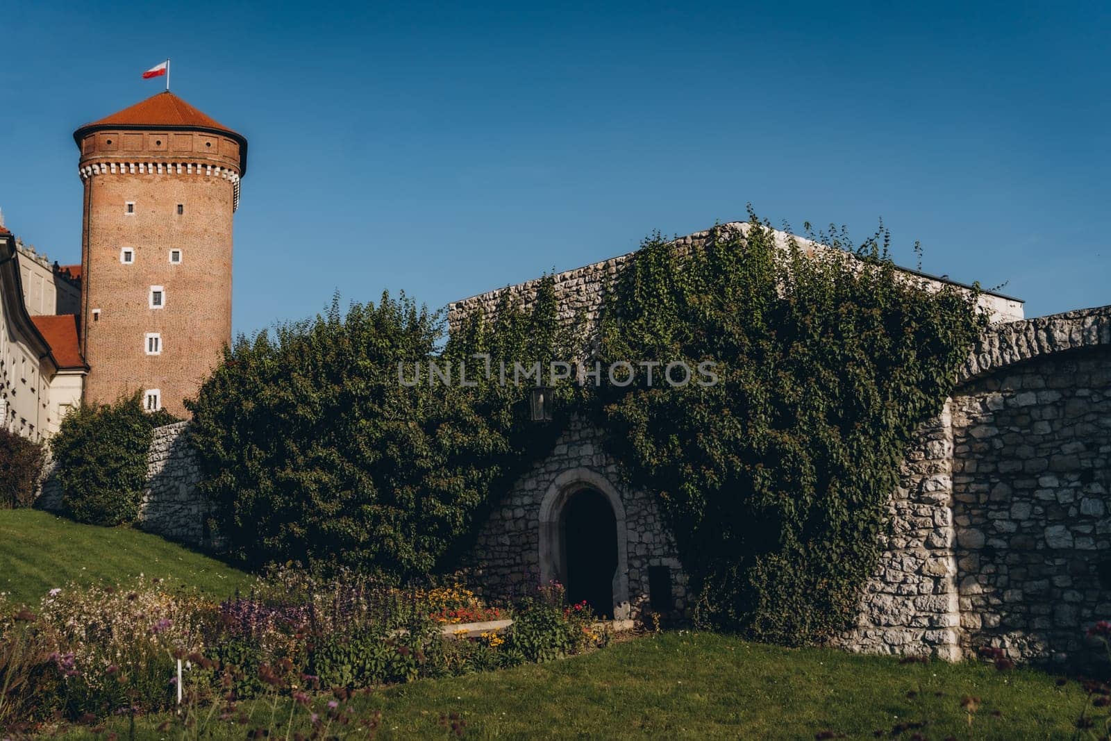 Stone tower and wall, green garden of Wawel Royal Castle complex in Krakow, Poland