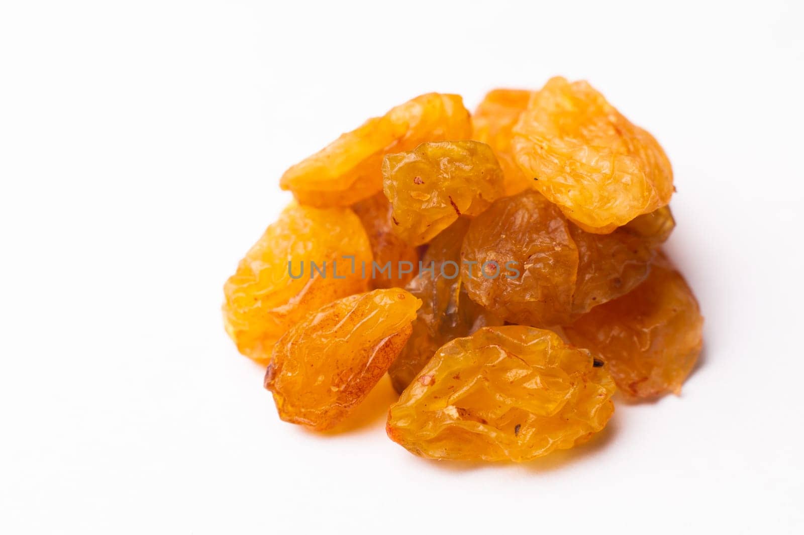 Raisins lie in a pile on a white background, close-up of the texture of the raisins, macro shot.