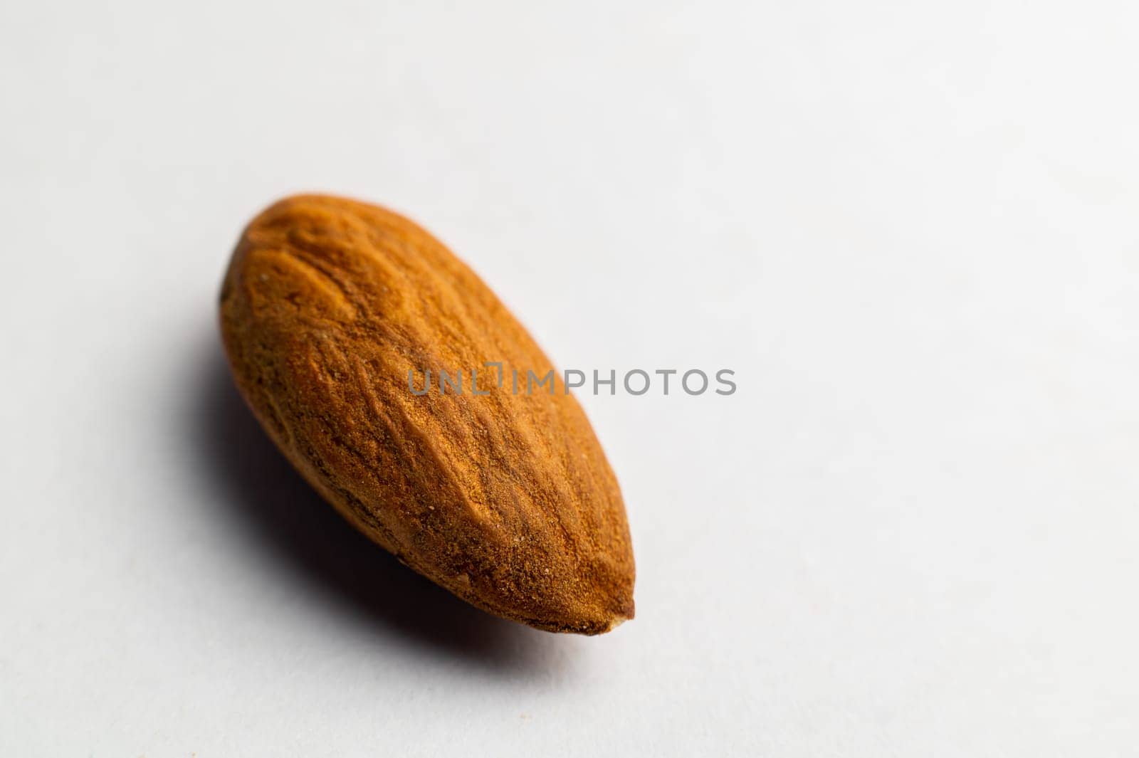 Almonds on a white background, close-up of the seed from the side. One nut macro shot.