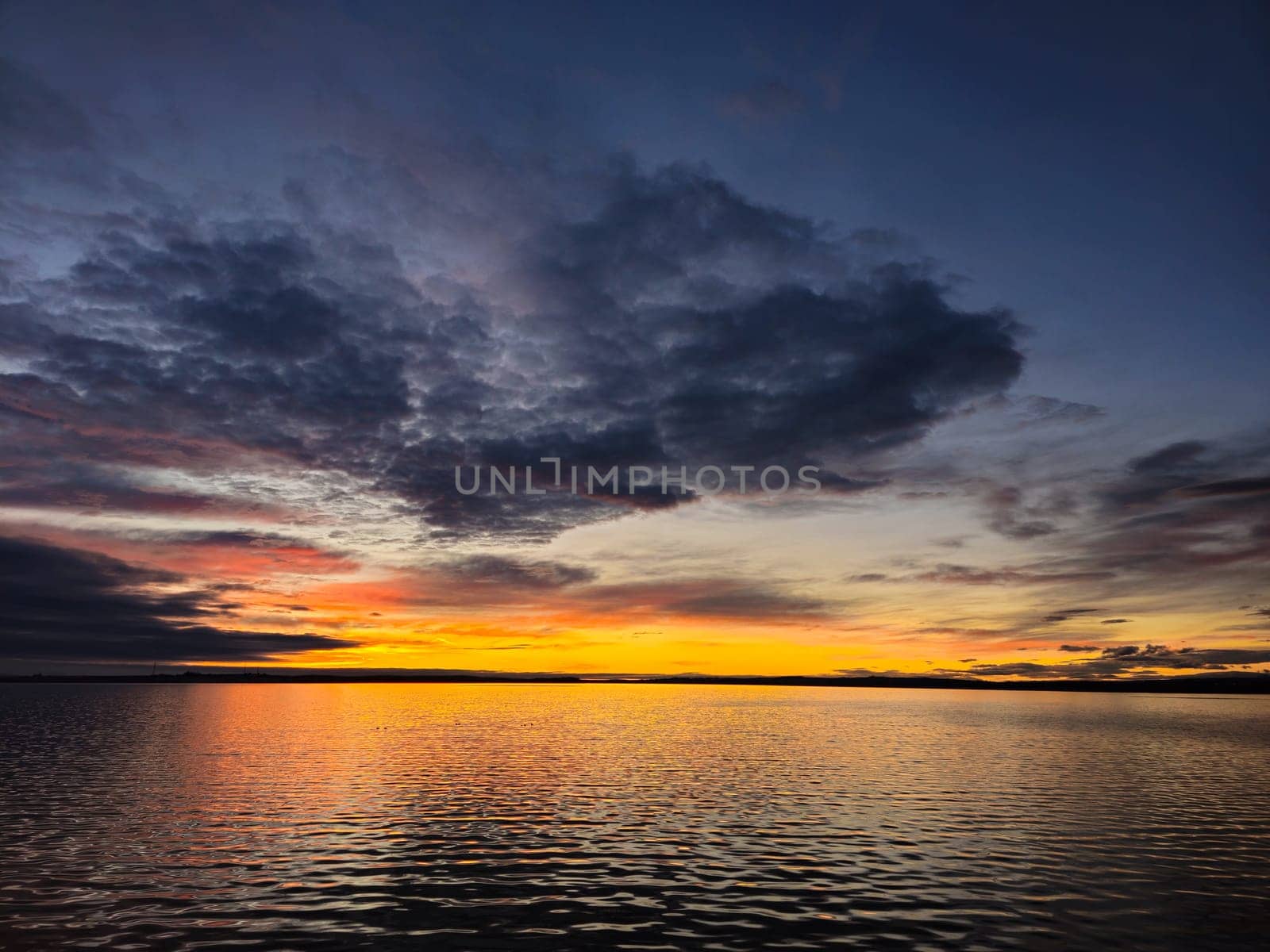 a sunset over a body of water with a cloudy sky by txking