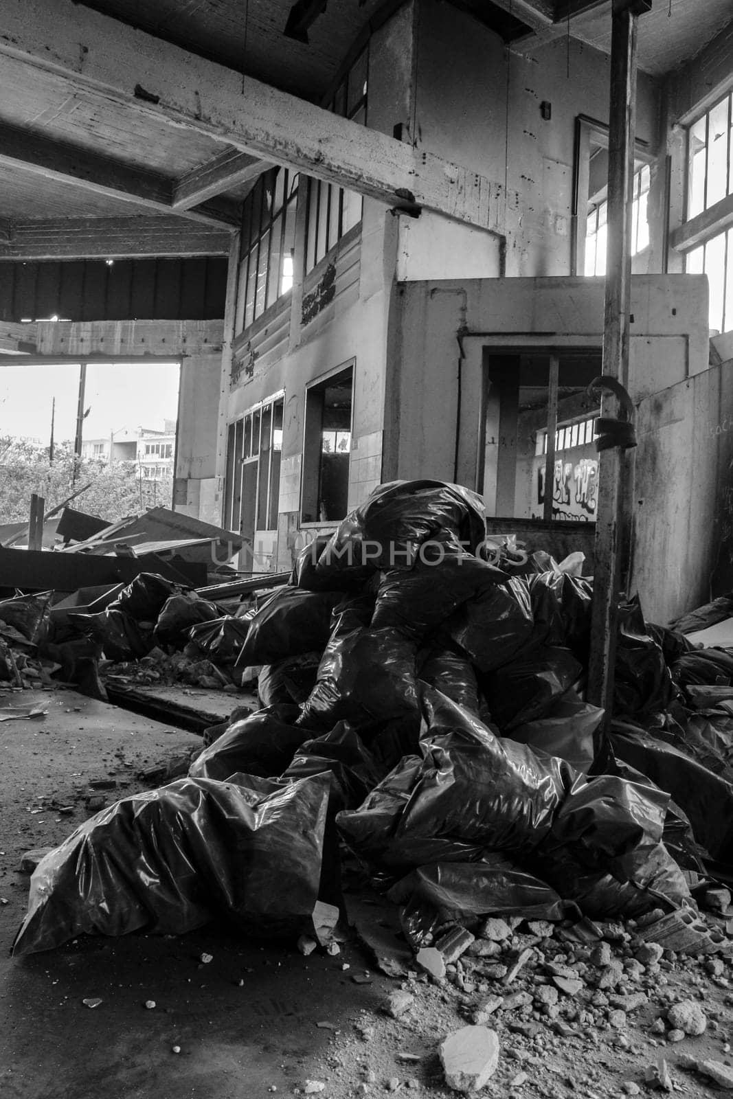 Peer into the gritty underbelly of urban life with this arresting image capturing piles of trash bags amidst the desolation of abandoned city streets.