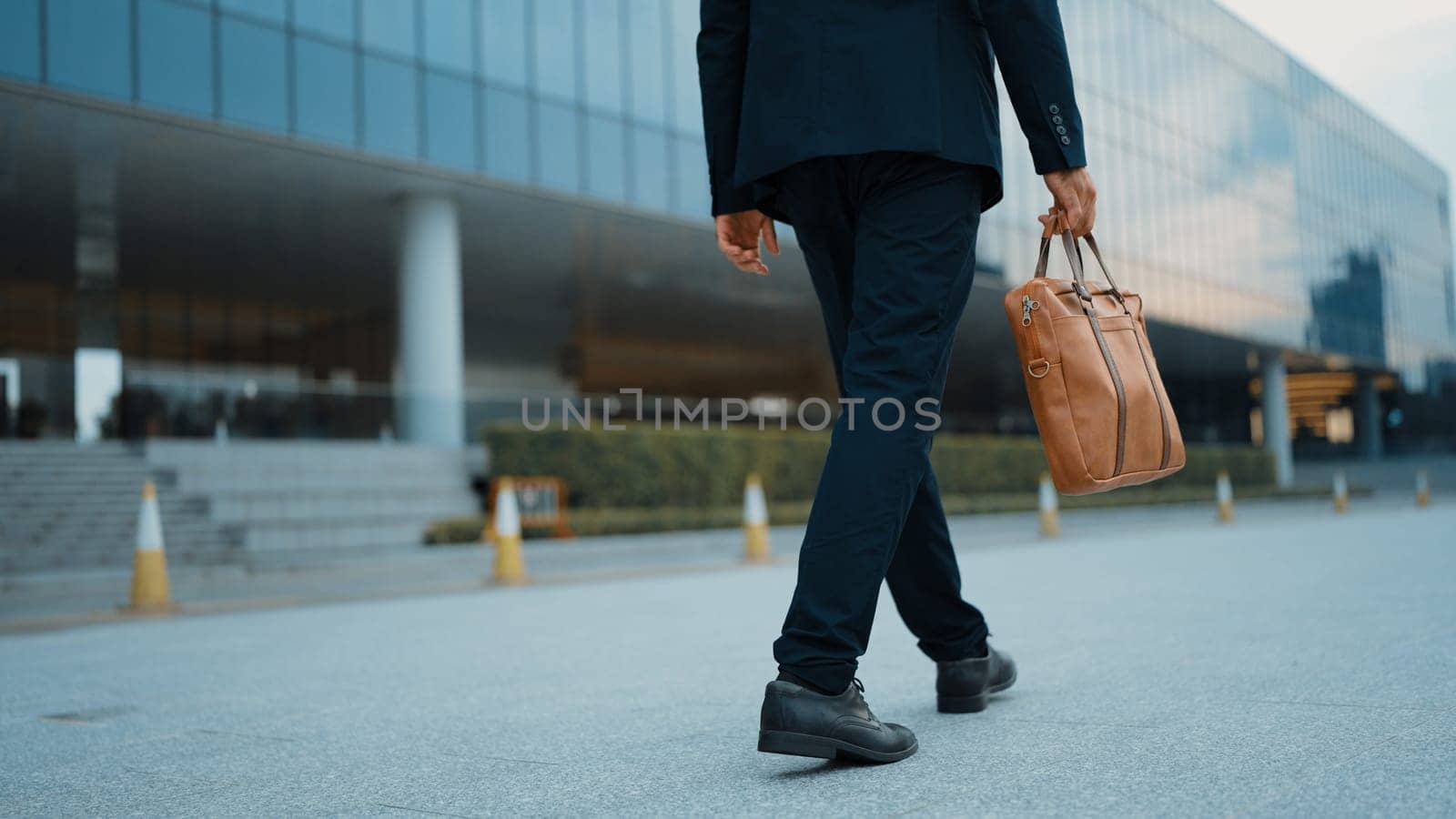 Closeup of skilled business man leg walking while holding bag. Cropped image of project manager focus on leg. Traveling, moving, journey, getting a new position, job changing. Back view. Exultant.