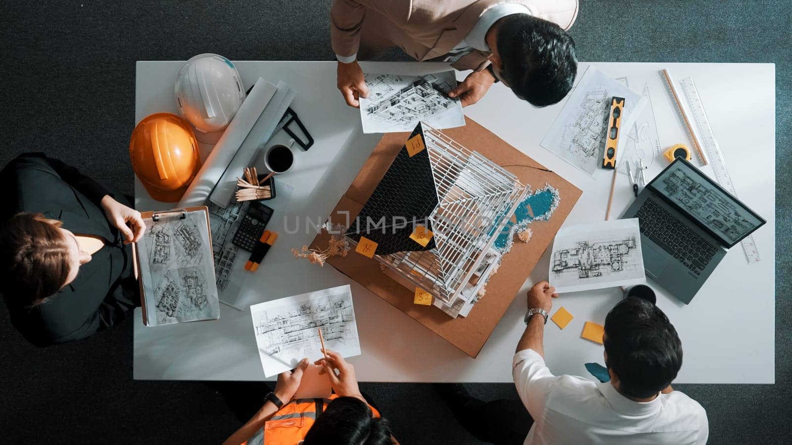 Top view of manager handed blueprint to professional engineer team at meeting table with house model and project plan. Group of architect discussing about design while receive document. Alimentation.