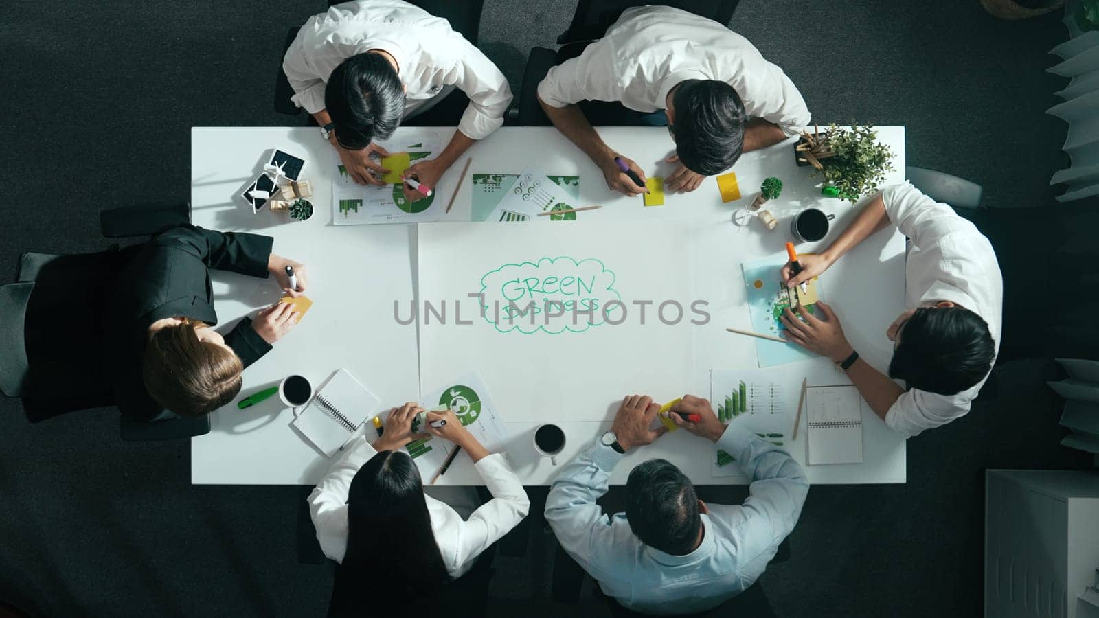 Top down view of business team discussing about using clean energy and sustainable investment at meeting table with wind mill, document with environmental graph and wooden house model. Alimentation.