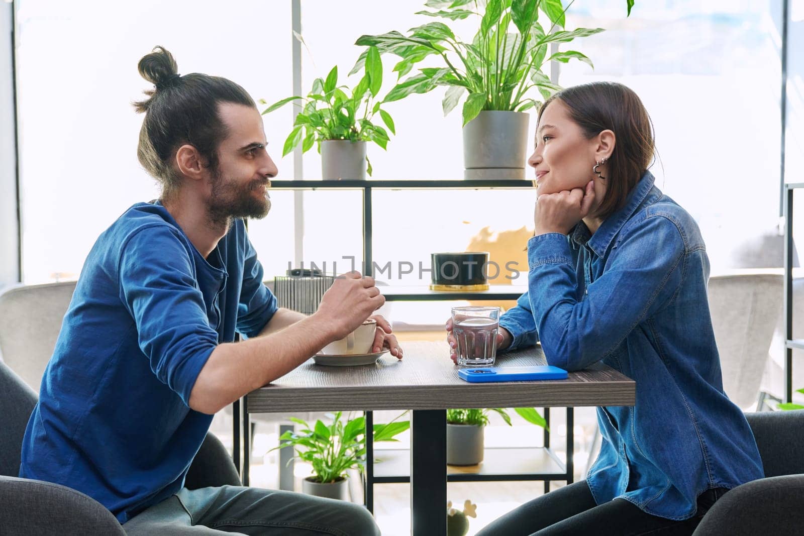 Laughing cheerful young couple sitting together in cafe by VH-studio