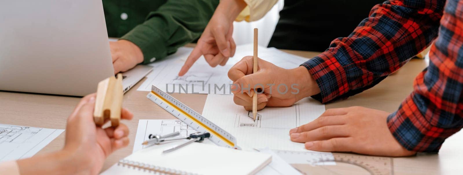 Professional architect team discussion about architectural project on meeting table with blueprint and wooden block scatter around at modern office. Closeup. Focus on hand. Delineation.