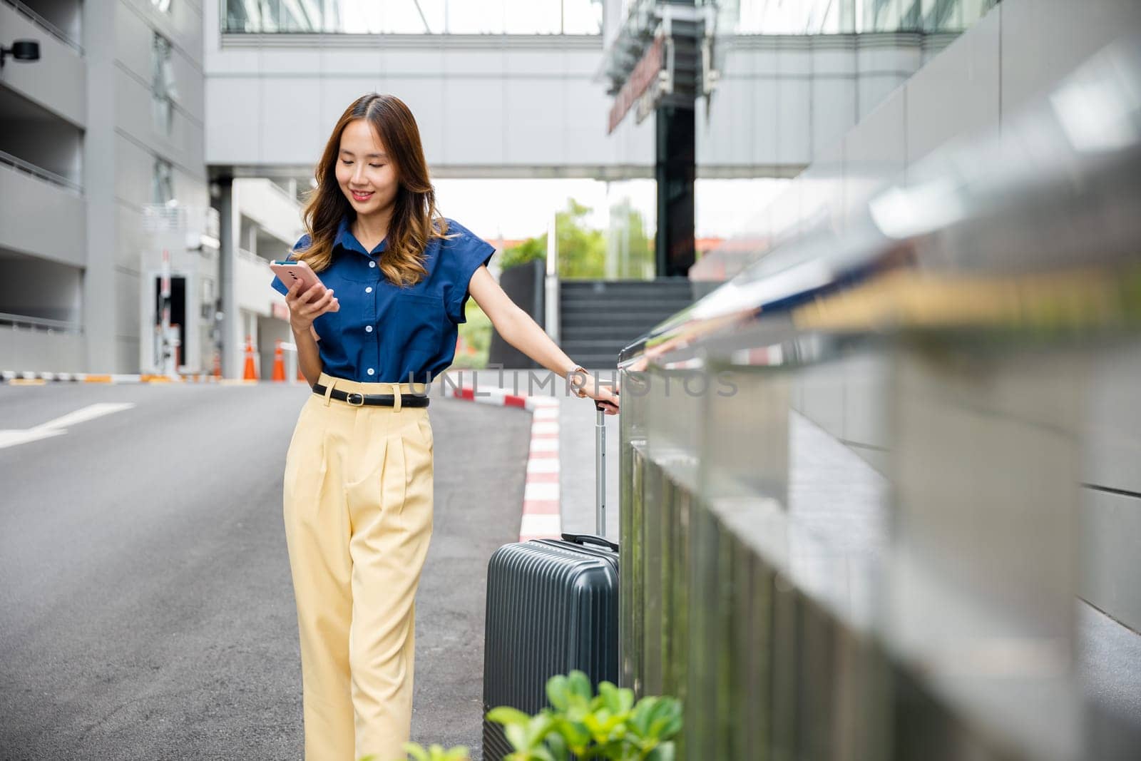 Happy woman in blue shirt texting on smartphone and walking in the city. Young girl using cell phone app to stay connected and enjoy her day outside.