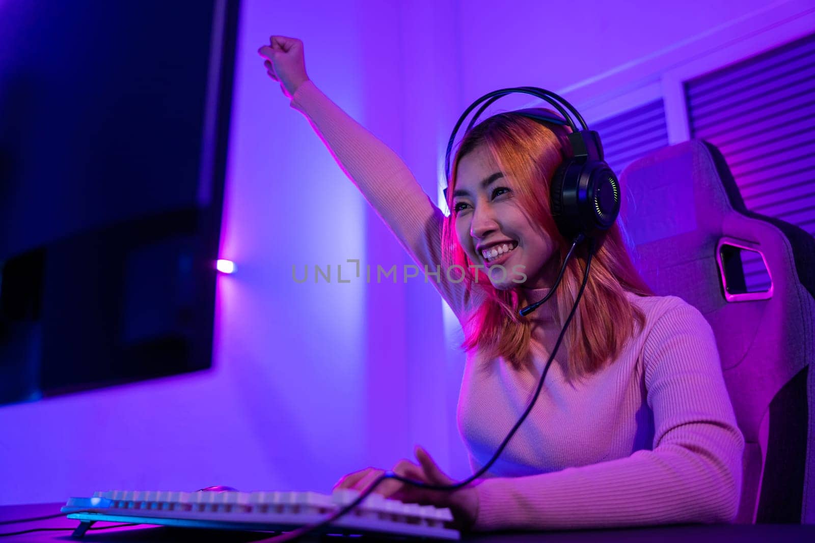 Winning. Young woman in gaming headphones playing video game online at home neon room feel excited, Happy Gamer young plays online video games computer she raises hands to wins tournament, E-Sport