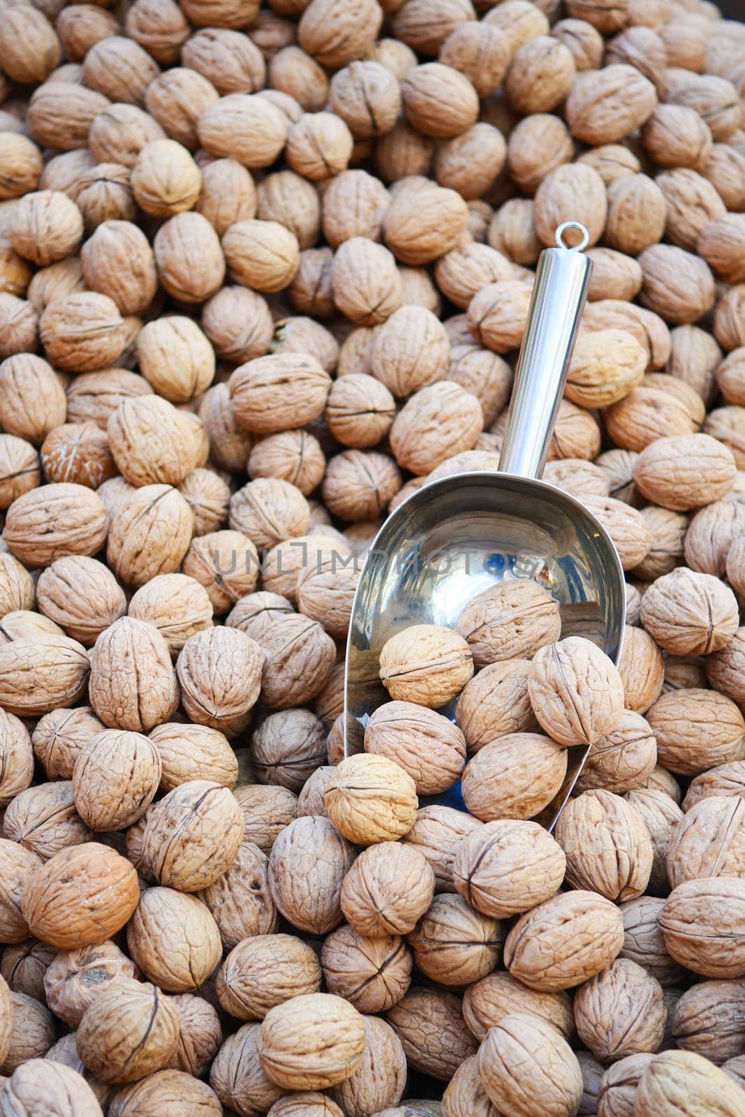 A scoop of walnuts, a superfood, rests on a stack of nuts seeds by towfiq007